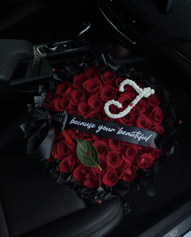 Signature Rose Bouquet — red roses in black wrap with a personalised initial and ribbon message